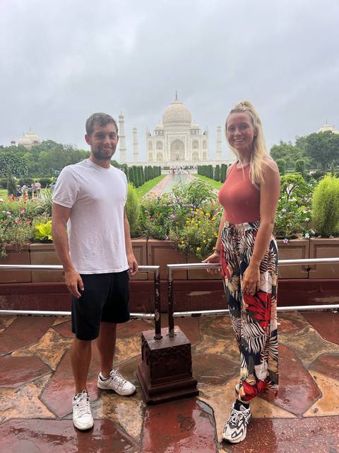 Couple posing on a terrace with the Taj Mahal in view.