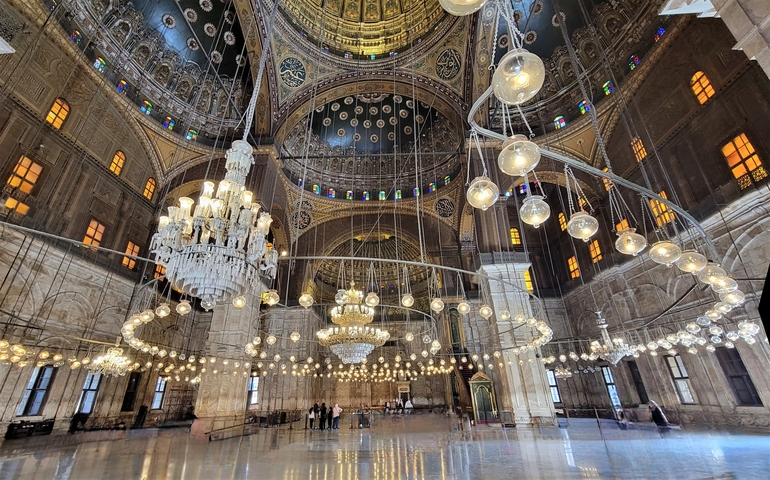 Interior of a grand mosque with elaborate chandeliers.