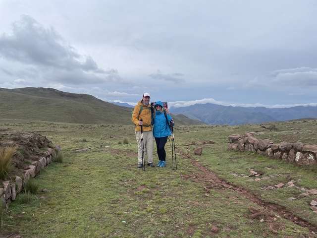 Couple posing on a grassy path with trekking poles.