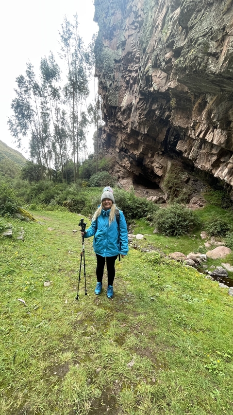 Person posing with trekking poles near a rock formation.