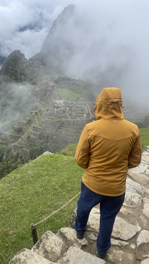 Person in a brown jacket overlooking Machu Picchu.