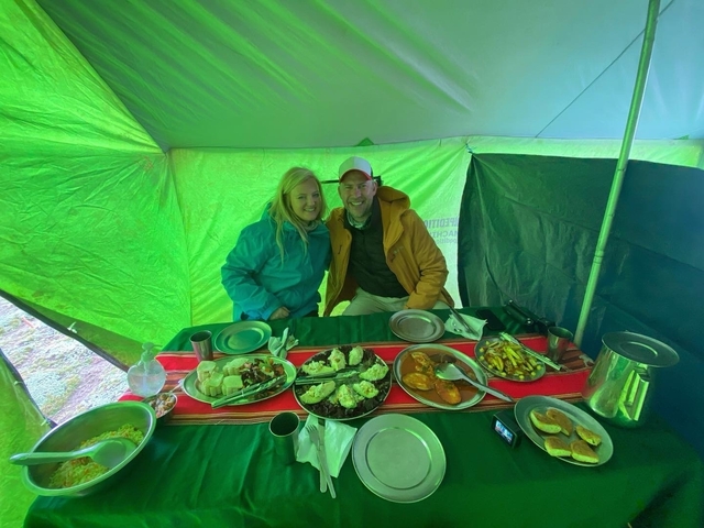 Two people sitting at a dining table with various dishes.