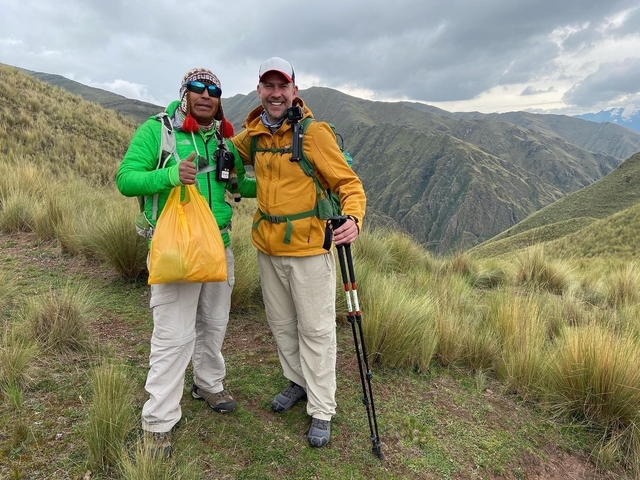 Two trekkers posing with trekking poles in the mountains.