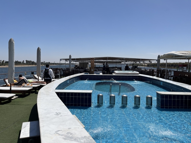 People relaxing by a pool on a boat deck.