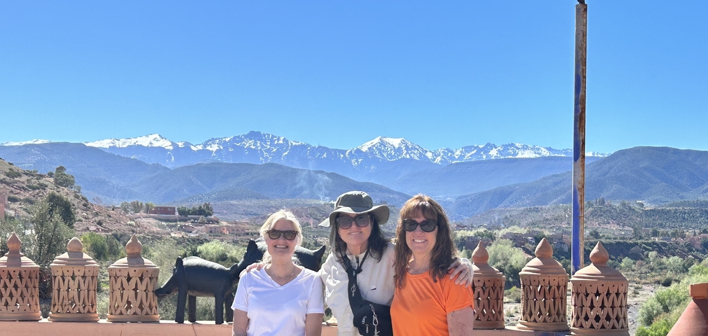       Three people posing with a backdrop of snow-capped mountains.
  