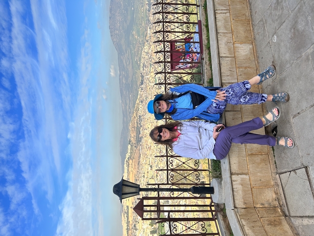       Two people posing with a panoramic view.
  