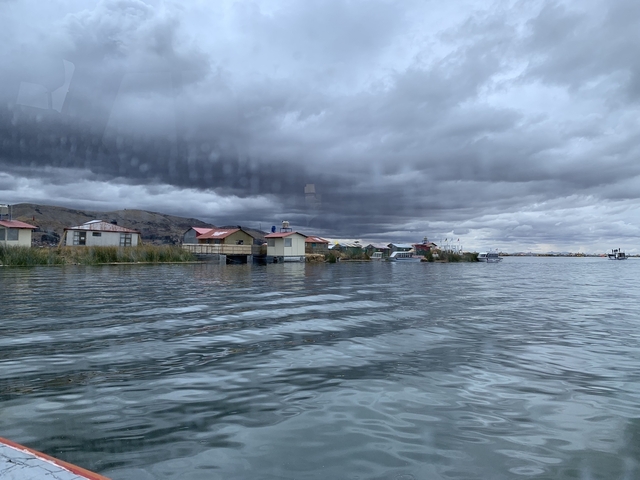 Floating houses on a lake under a cloudy sky.