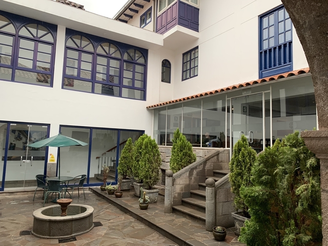       Courtyard of a building with plants and seating.
  