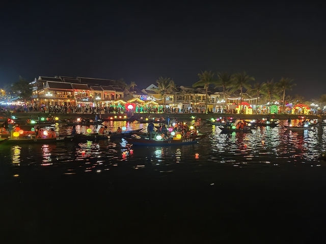 Night market with boats and lights on a river.