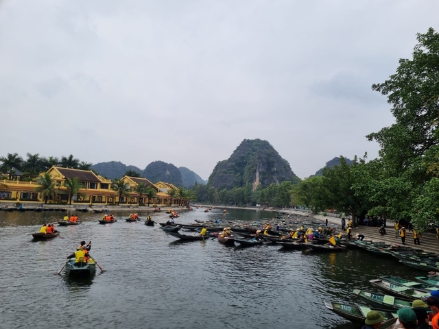       Boats on a river with karst mountains and yellow buildings in the background.
  