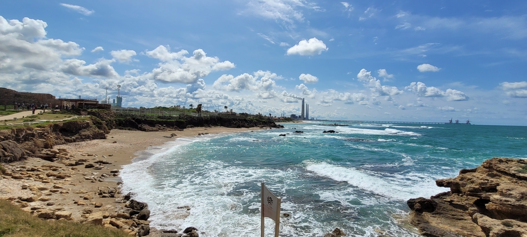 Coastline with rocky beach and distant city skyline.