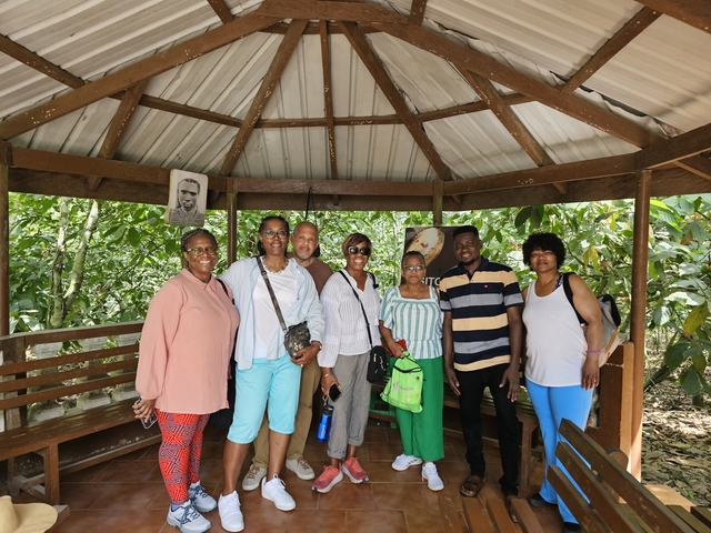 Group of people in a wooden gazebo in a lush setting.