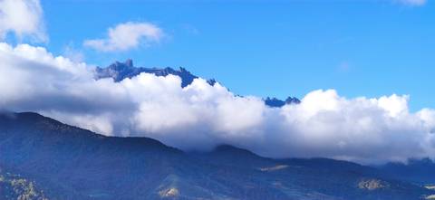       Mountain range with peaks above the clouds on a clear day.
  