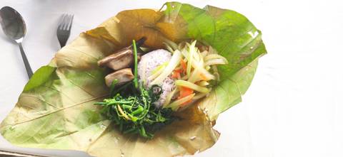       Traditional meal served on a large leaf at an outdoor setting.
  
