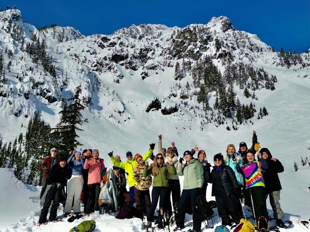 Group of people celebrating outdoors with snowy mountains in the background.