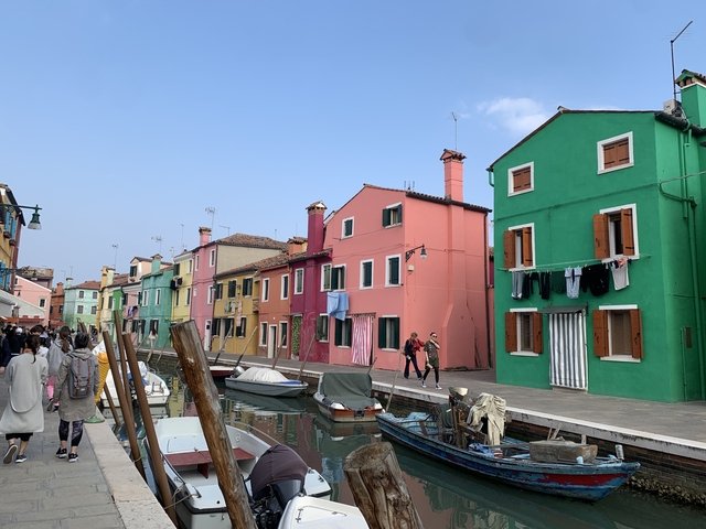 Colorful houses along a canal with boats and people walking.