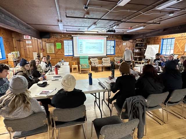 People in a rustic meeting room with presentation on the screen.