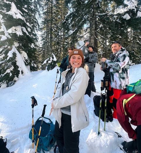 People walking with hiking gear in a snowy forest area.