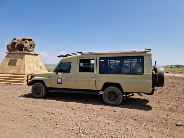Safari vehicle parked near a monument with skull sculptures.
