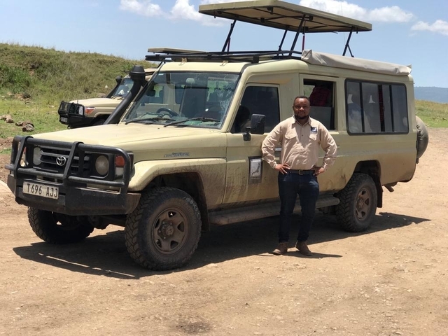 Person standing in front of a safari vehicle.