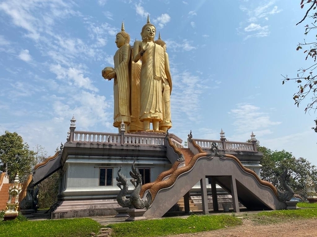 Golden statue of two standing figures atop a temple.
