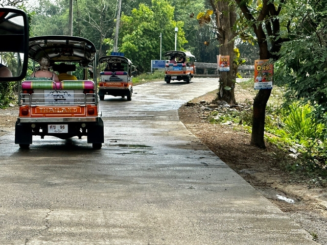 Tuk-tuks driving down a wet road, rear view.