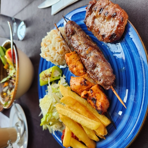       Assortment of grilled meats and vegetables on a blue plate.
  
