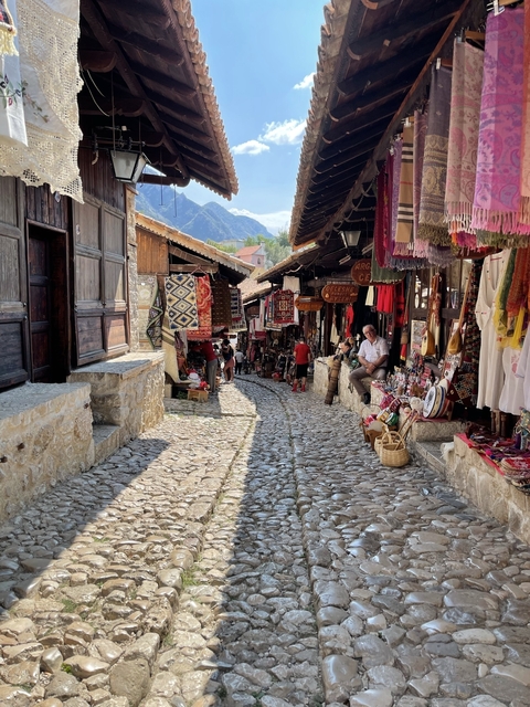       Bustling narrow street market with shops and people.
  
