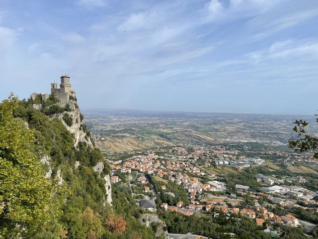       Castle on a cliff overlooking a town and landscape.
  