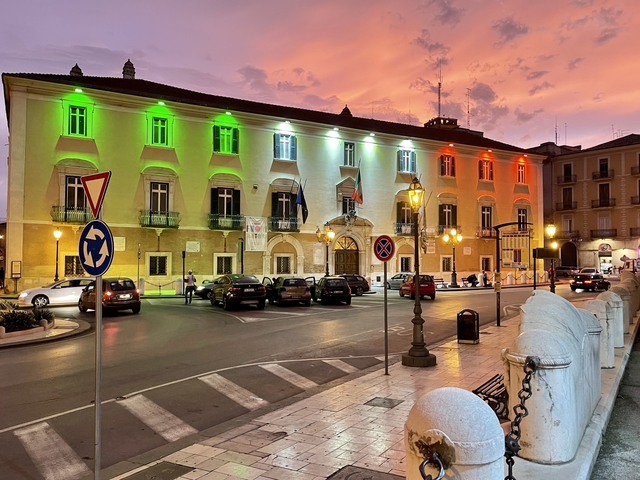       City building lit with green, white, and red lights representing Italian flag.
  