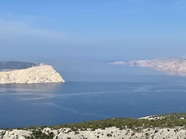       Scenic coastal view with clear blue water and mountains.
  