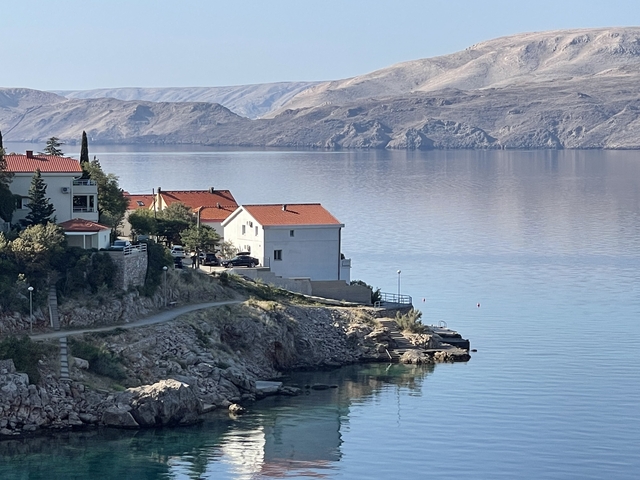       Coastal houses with red roofs overlooking calm sea.
  