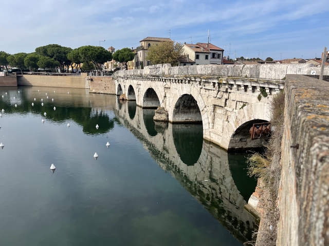       Ancient stone bridge over a calm canal.
  