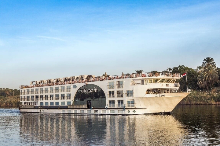       Large luxury cruise ship on the Nile River with people on deck.
  