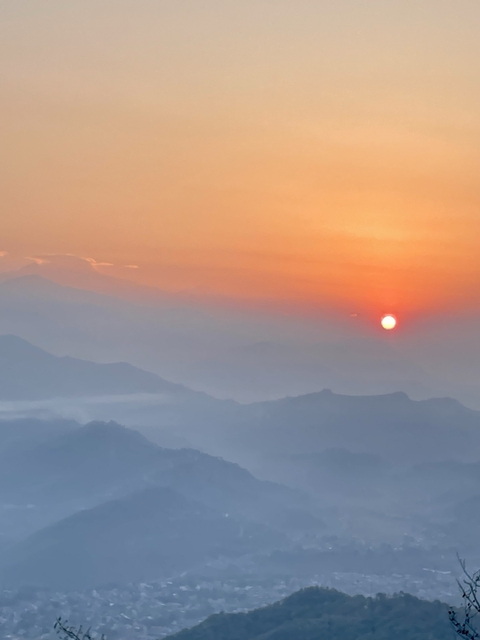 Sunrise over misty mountains with soft lighting.