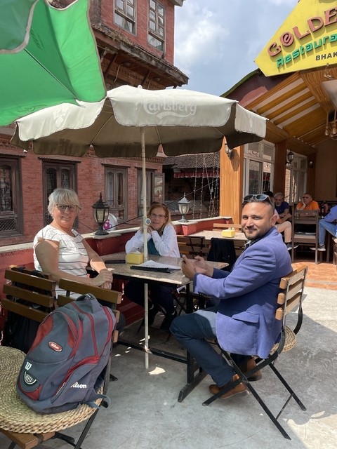 Group of people dining outdoors at a cafe with traditional brick buildings.