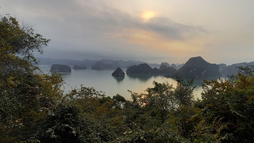 Stunning view of Halong Bay with limestone karsts and a delicate sunset.