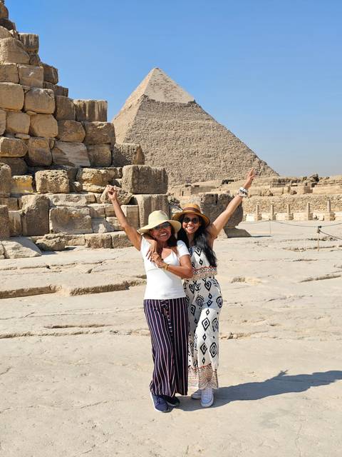       Two people posing in front of the Great Pyramid of Giza.
  