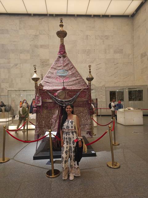       Person posing beside an ornate display in a museum.
  