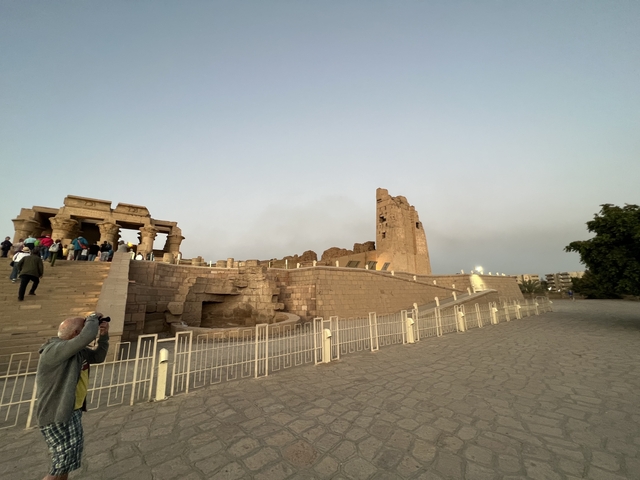       Ruins with walls and columns, tourists exploring.
  
