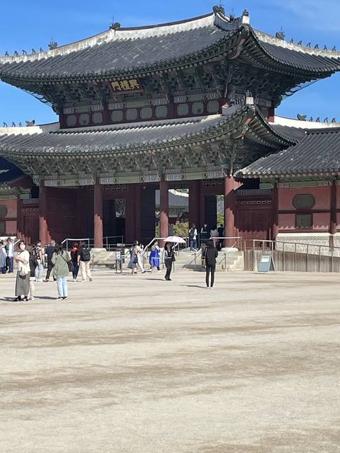       Traditional Korean gate with people standing in front.
  