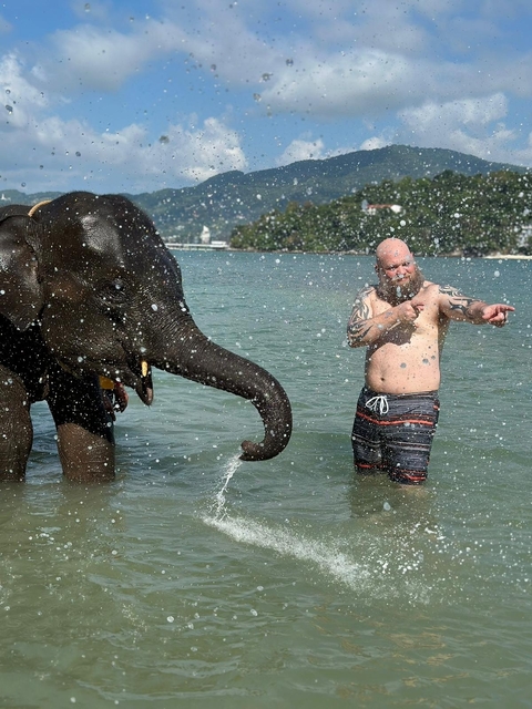       Man playing with an elephant in the sea.
  