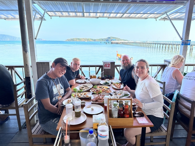       People dining outdoors by the sea.
  