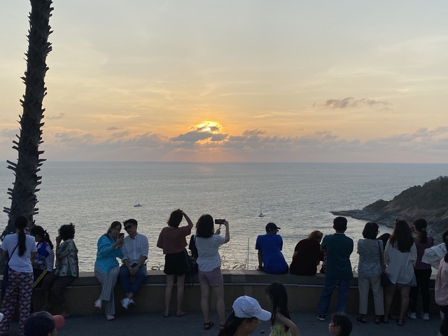       People watching a sunset over the ocean.
  