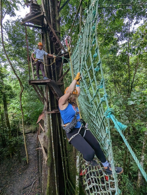 Person climbing on a hanging net with safety gear.