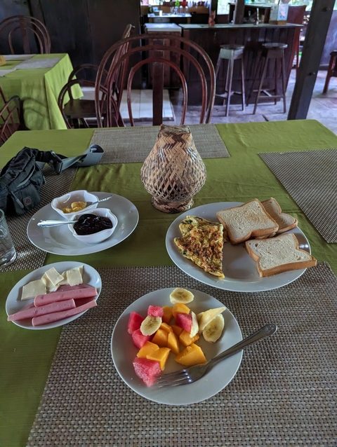       Breakfast spread on a table with bread, omelette, and fruits.
  