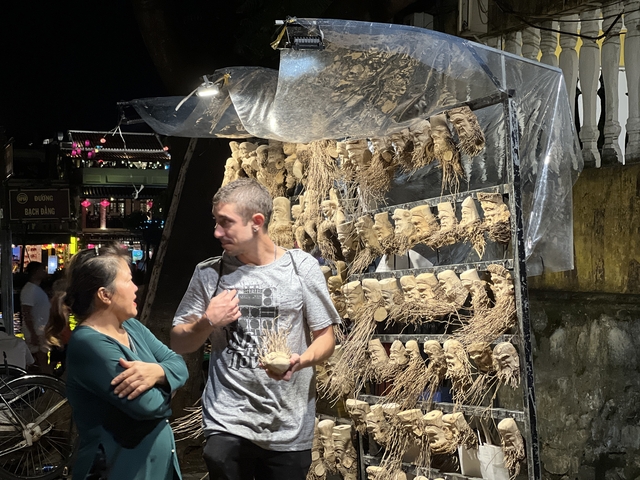 Two people examining handcrafted masks in a night market.
