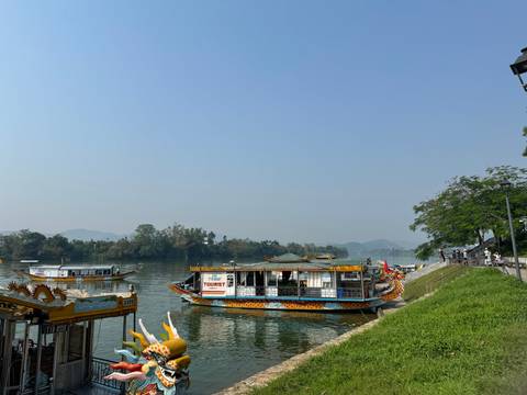       Colorful boats on a river with scenic hills in the background.
  