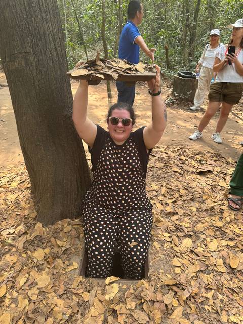       Person emerging from a trap door in a wooded area.
  