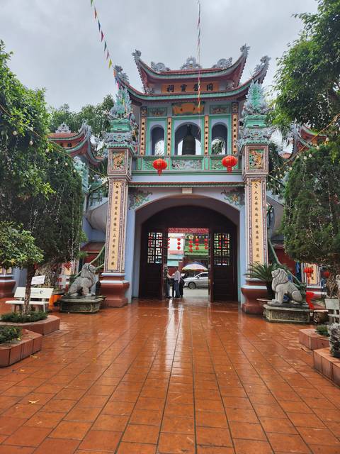       Decorative entrance of a temple with intricate carvings and red lanterns.
  